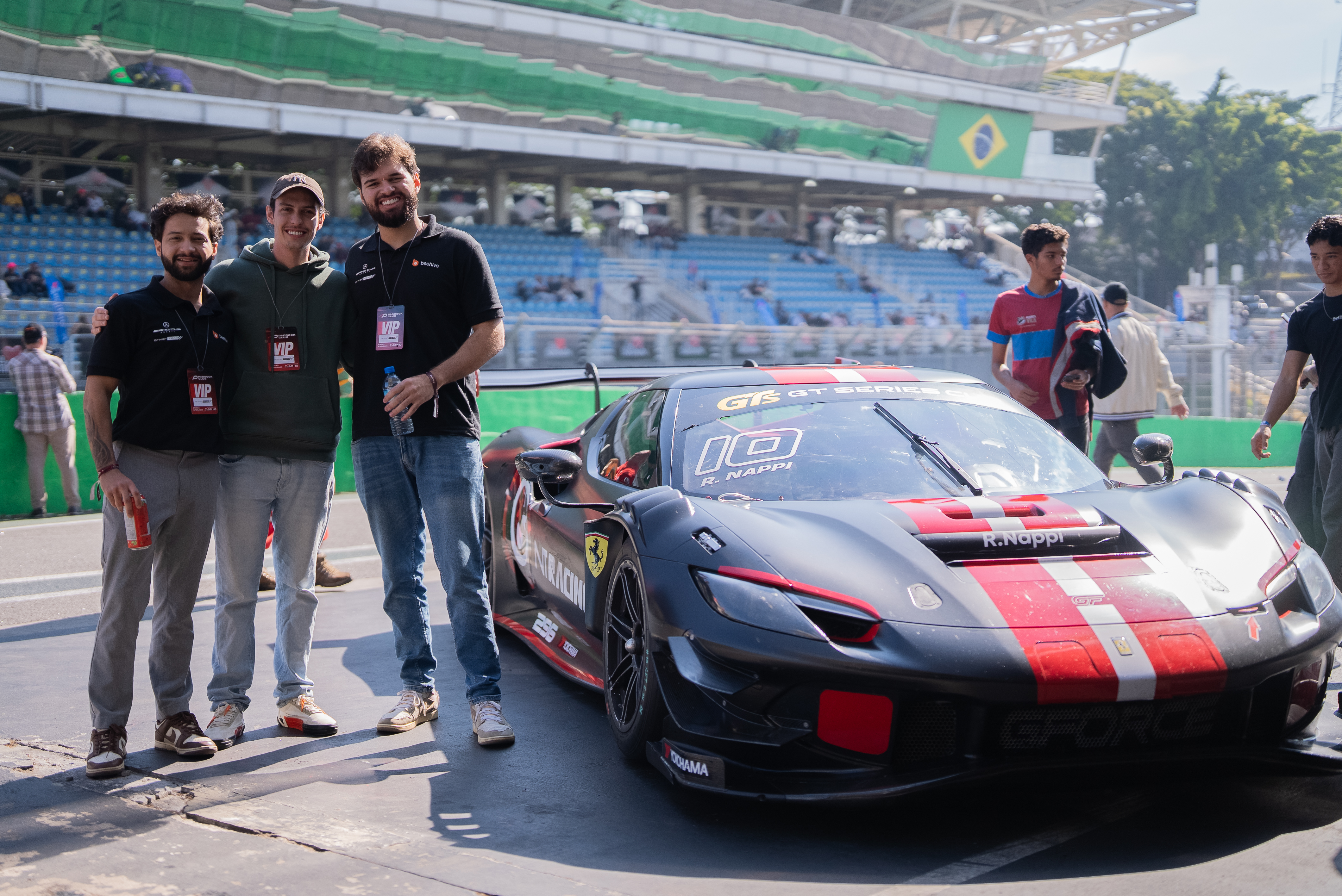 Os fundadores da Beehive ao lado de uma Ferrari, no autódromo de Interlagos.